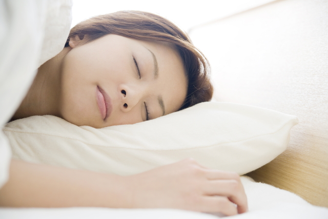 布団乾燥機にかけた布団で寝る女性