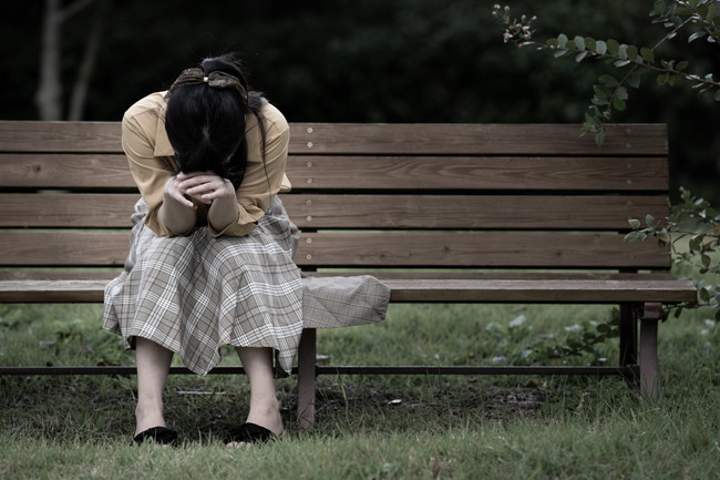 ベンチに座って落ち込む女性